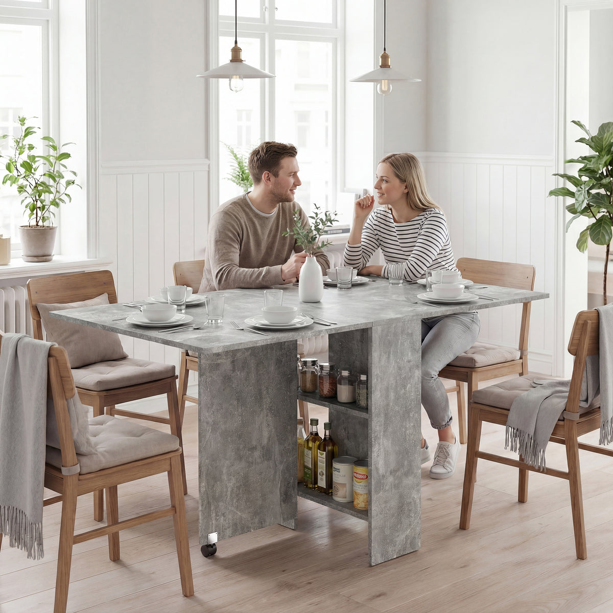 Tavolo pieghevole grigio aperto con due ripiani centrali e ruote, esempio di utilizzo in sala da pranzo